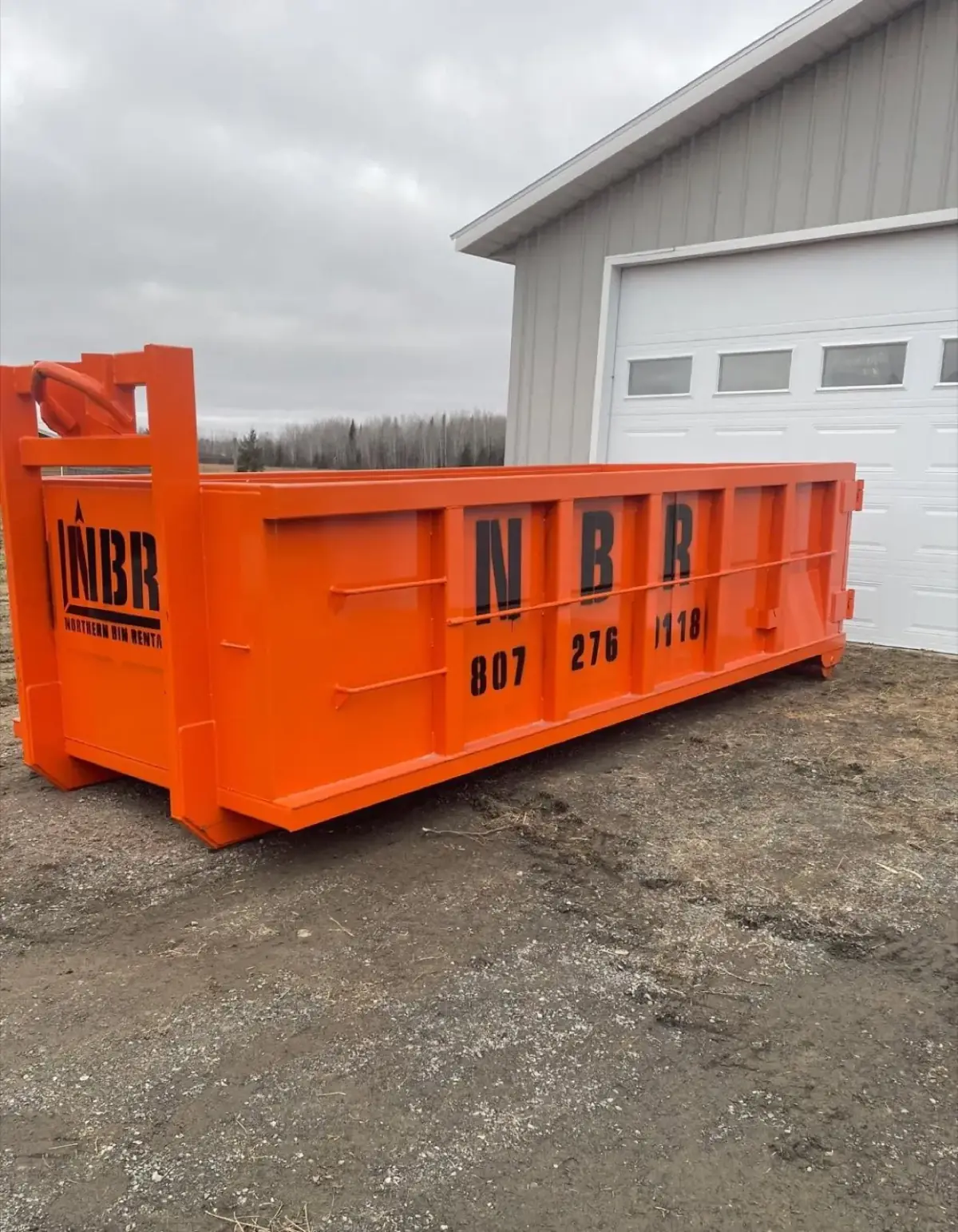 Northern Bin Rentals orange roll-off bin dropped and ready on a Fort Frances property